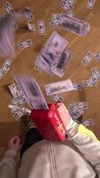 vertical pov first person view Man wearing a tracksuit is shooting fake money with a red toy gun on a wooden floor, creating a playful and exciting scene video