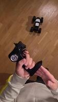 vertical POV First-person view of a person holding a remote control and maneuvering a radio-controlled car on a polished parquet floor, creating a playful and engaging scene video