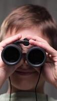 vertical close-up portrait Young boy holds binoculars to his eyes, engaging in imaginative exploration and discovery, his face lit with a sense of wonder and adventure video