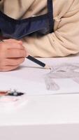 vertical Close-up view of a child artist sketching a bunny rabbit face with a pencil on white paper. The focus highlights the creativity and concentration involved in the drawing process video
