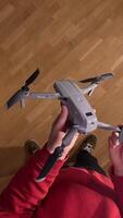 vertical pov first person view man holds modern folding quadcopter drone in hands. Person mounting propellers on a gray foldable quadcopter drone, preparing it for flight video