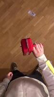 vertical pov first person view Man is throwing fake dollar bills in the air using a red toy money gun, creating a playful scene of scattered cash on a wooden floor video