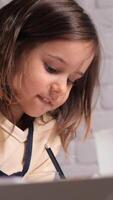 vertical a little girl enthusiastically draws with a pencil. child at home at the table diligently and concentratedly draws with pencils. video