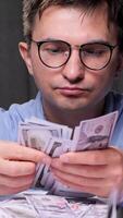 vertical office worker man Accountant carefully counting a stack of us dollar bills at his desk late at night, surrounded by financial documents and folders, diligently managing budget video