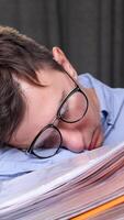vertical Exhausted office worker sleeps on a stack of documents, overwhelmed by work stress and fatigue. Balancing work and mental health is a challenge video
