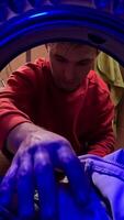 vertical pov Man loading dirty clothes into the washing machine. Man opening the door of the washing machine. View from inside the washing machine. Man in a modern bathroom video