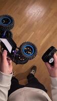 vertical pov First-person view of a person using a remote control to operate a radio-controlled car on a wooden floor, providing a playful and engaging perspective on indoor hobbies video