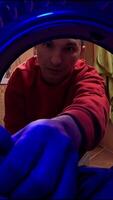 vertical pov Young man pulling clothes out of washing machine in bathroom. View from inside washing machine. Young man is retrieving laundry from a front-loading washing machine video