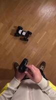 vertical Person holding a remote control while playing with a radio controlled car on a parquet floor, seen from a first-person perspective. A man throws a radio controlled car on the floor video