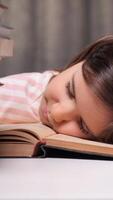 vertical the little girl got tired of learning to read and fell asleep on a book. The concept of children getting tired of learning. The little girl read enough fairy tales and fell asleep video