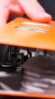 vertical close-up Office worker stacks folders with documents. Office worker is consulting documents inside an orange binder, potentially reviewing important paperwork or preparing for a meeting video