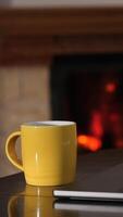 vertical concept of a cozy home workspace with a computer by the fireplace. Freelancer is working on a laptop with a cup of coffee nearby. The fireplace is lit in the background, video