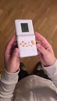 vertical pov First person view Immerse in nostalgia with a man playing a retro handheld game console, evoking 80s and 90s memories with pixelated graphics. Enjoy the old-school fun on the go video