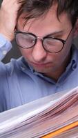 vertical Young business man with eyeglasses having headache from too much paperwork and holding his head with hand while working in office video