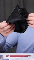 vertical A man, upset by the lack of money, clutches his head. The man has run out of money. Office worker showing empty wallet, struggling with financial problems, having no money video