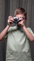 vertical Boy learning photography is using an old rangefinder camera, carefully adjusting focus and framing the shot against a gray backdrop video
