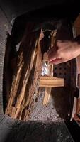 vertical top view inside fireplace. Person lighting kindling in a fireplace creates a warm atmosphere as smoke rises from the burning wood. The scene evokes feelings of comfort and cozines video