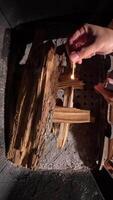 vertical top view inside fireplace Person lights kindling in a fireplace using a match, creating a bright flame. The warmth and glow enhance the cozy atmosphere video