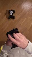 vertical POV First-person view of a person holding a remote control and maneuvering a radio-controlled car on a polished parquet floor, creating a playful and engaging scene. First person view video