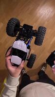 vertical pov Person holding a radio-controlled car upside down and the remote control, ready to play inside a house with a parquet floor video