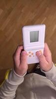 vertical pov First person view Boy plays a retro handheld game at home, lost in nostalgia and fun, enjoying childhood memories on a cozy parquet floor video