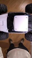 vertical pov man throws a model car up into the air. First-person view of a person Holding a radio-controlled car indoors on a wooden floor, ready to play and have fun video