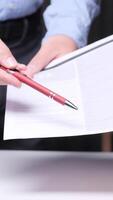 vertical Confident office worker showing where to sign on document, emphasizing importance. Neat desk, binders, notebook convey professionalism video