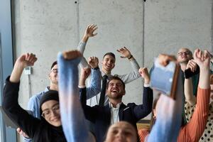 A diverse team of business professionals ecstatically celebrating their success in a modern office, expressing triumph and unity after achieving their goals photo