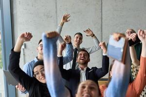 A diverse team of business professionals ecstatically celebrating their success in a modern office, expressing triumph and unity after achieving their goals photo