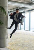 A businessman ecstatically jumping in a modern office, holding a briefcase in his hands, celebrating a moment of success and triumph. photo