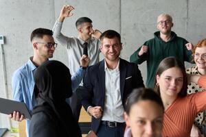 A diverse team of business professionals ecstatically celebrating their success in a modern office, expressing triumph and unity after achieving their goals photo