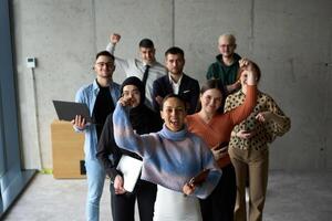 A diverse team of business professionals ecstatically celebrating their success in a modern office, expressing triumph and unity after achieving their goals photo