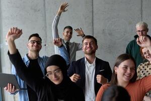 A diverse team of business professionals ecstatically celebrating their success in a modern office, expressing triumph and unity after achieving their goals photo