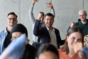 A diverse team of business professionals ecstatically celebrating their success in a modern office, expressing triumph and unity after achieving their goals photo