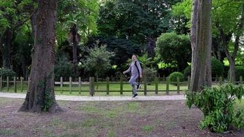 Actor in grey suit runs hopping along empty track in park video