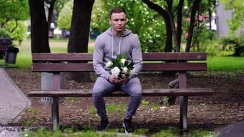 Handsome upset guy puts bouquet on bench and walks away video