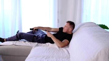 Muscular guy jumps on sofa presses remote controller buttons video