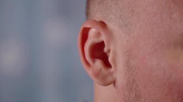 Expressive bald man shows ability to wiggle ears on blue video