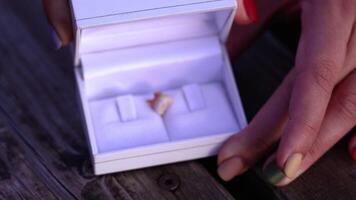 Manicured person hands open white engagement box with tooth video