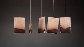 Brewed tea bags on threads hang waved on dark background video