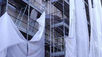 Torn cloth hangs on metal scaffolding against balconies video