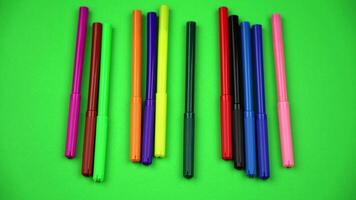 Multicolored markers with caps roll on sheet of green paper video