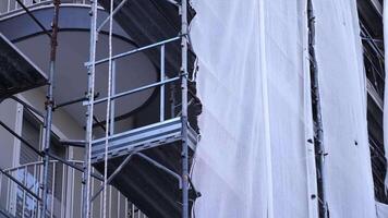 White torn fabric hangs on metal scaffolding at balcony video