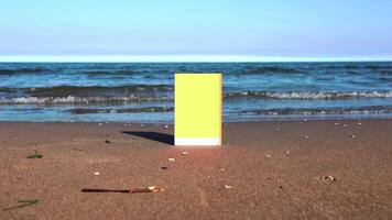 Yellow and white book stands on wet sand with small rocks video