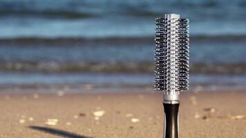 Hairbrush of grey and black colours stands on sandy beach video