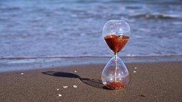 Sandglass clock with golden grains stands on sunny beach video