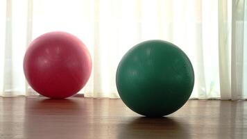 Exercise balls of pink and turquoise colours on wooden floor video