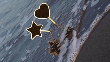 Foamy waves roll to blank star and heart nameplates in sand video