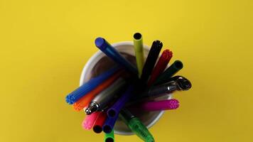 Motion above different color markers and pens in plastic cup video