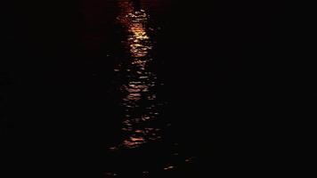 Sailing past path of yellow light reflected on water surface video